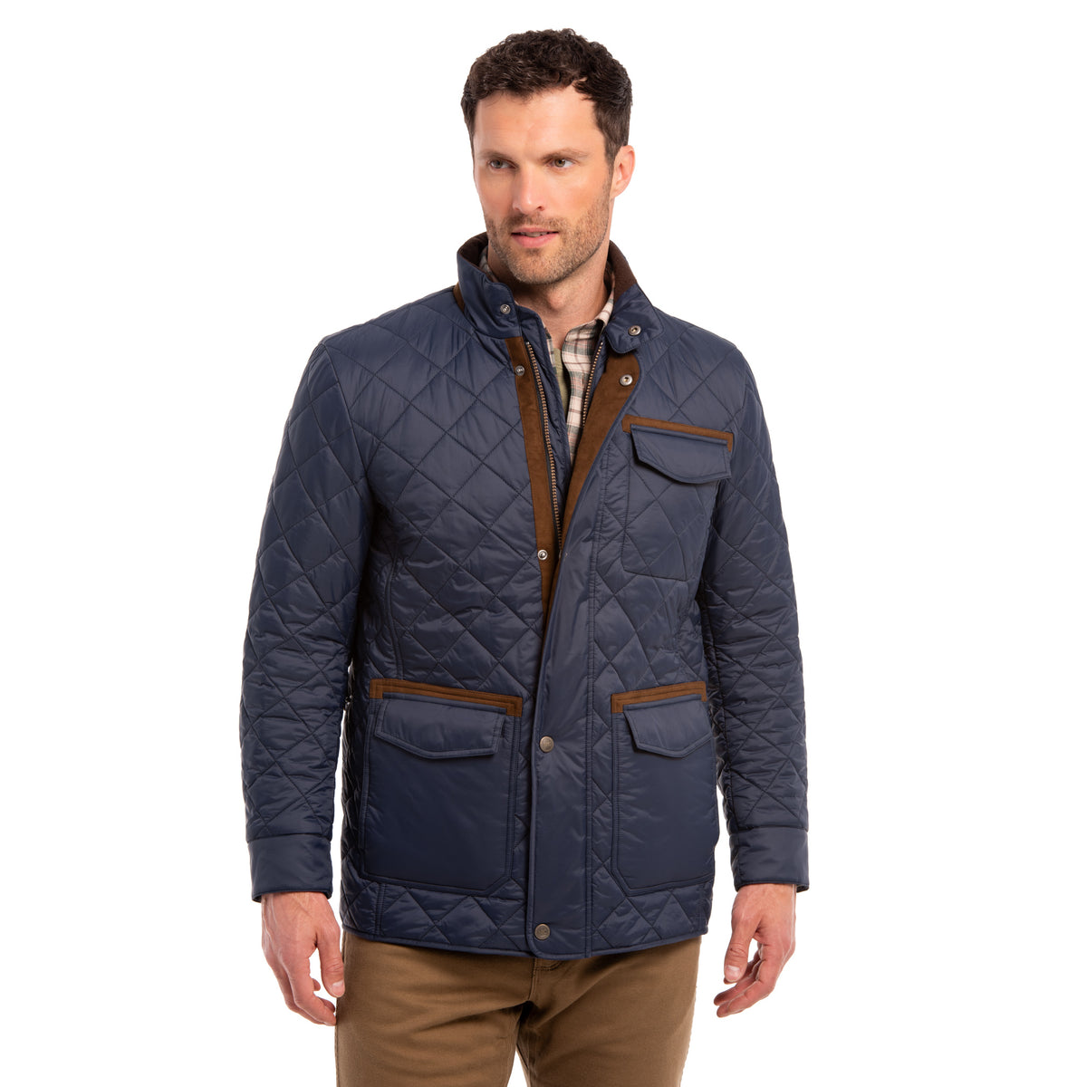 A man wearing a navy diamond-quilted nylon jacket with brown trim, a plaid shirt, and brown pants, photographed against a plain white background.