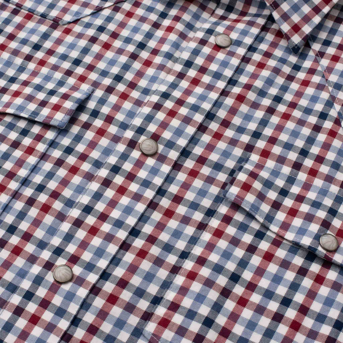 Close-up of men's Western shirt in red, blue and white check with pearl snaps.